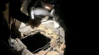 A ‍couple stands smiling in front of their tiny home.